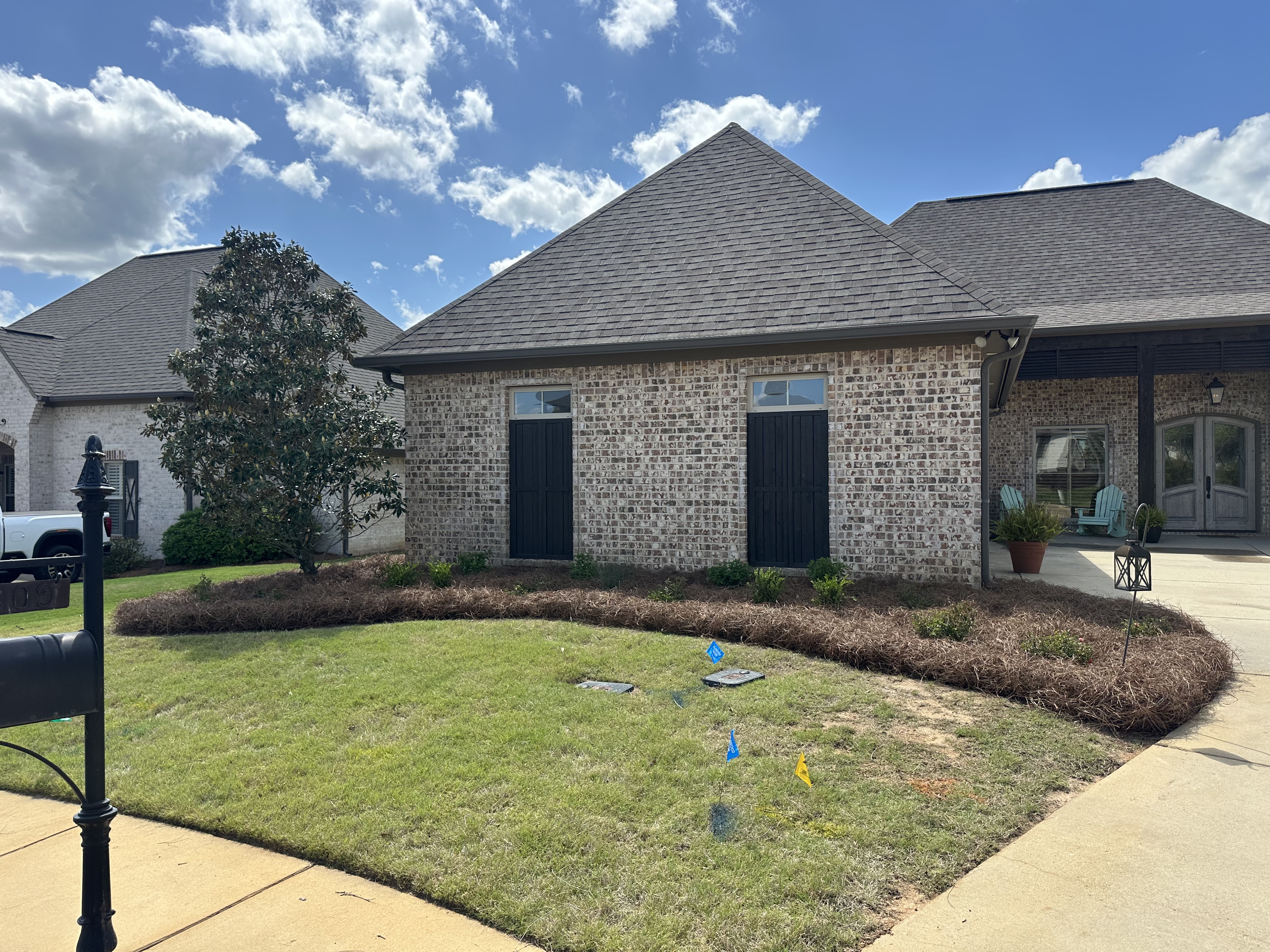 Fresh pine straw beds around brick home